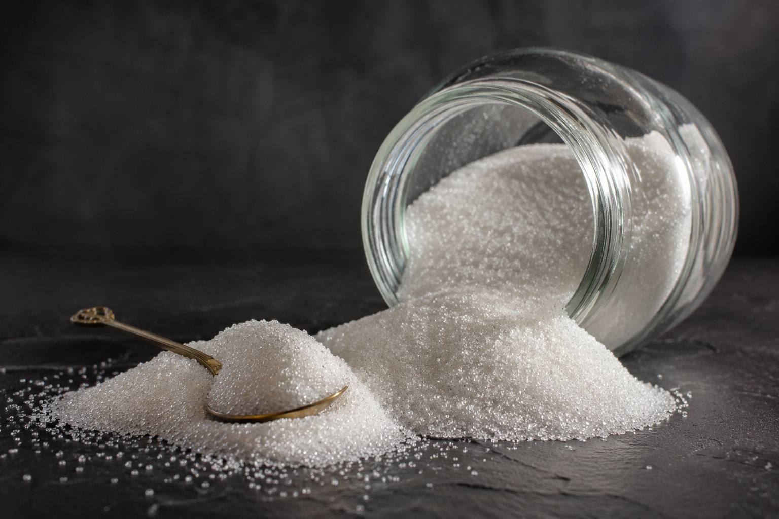 Refined white sugar spilling from a jar